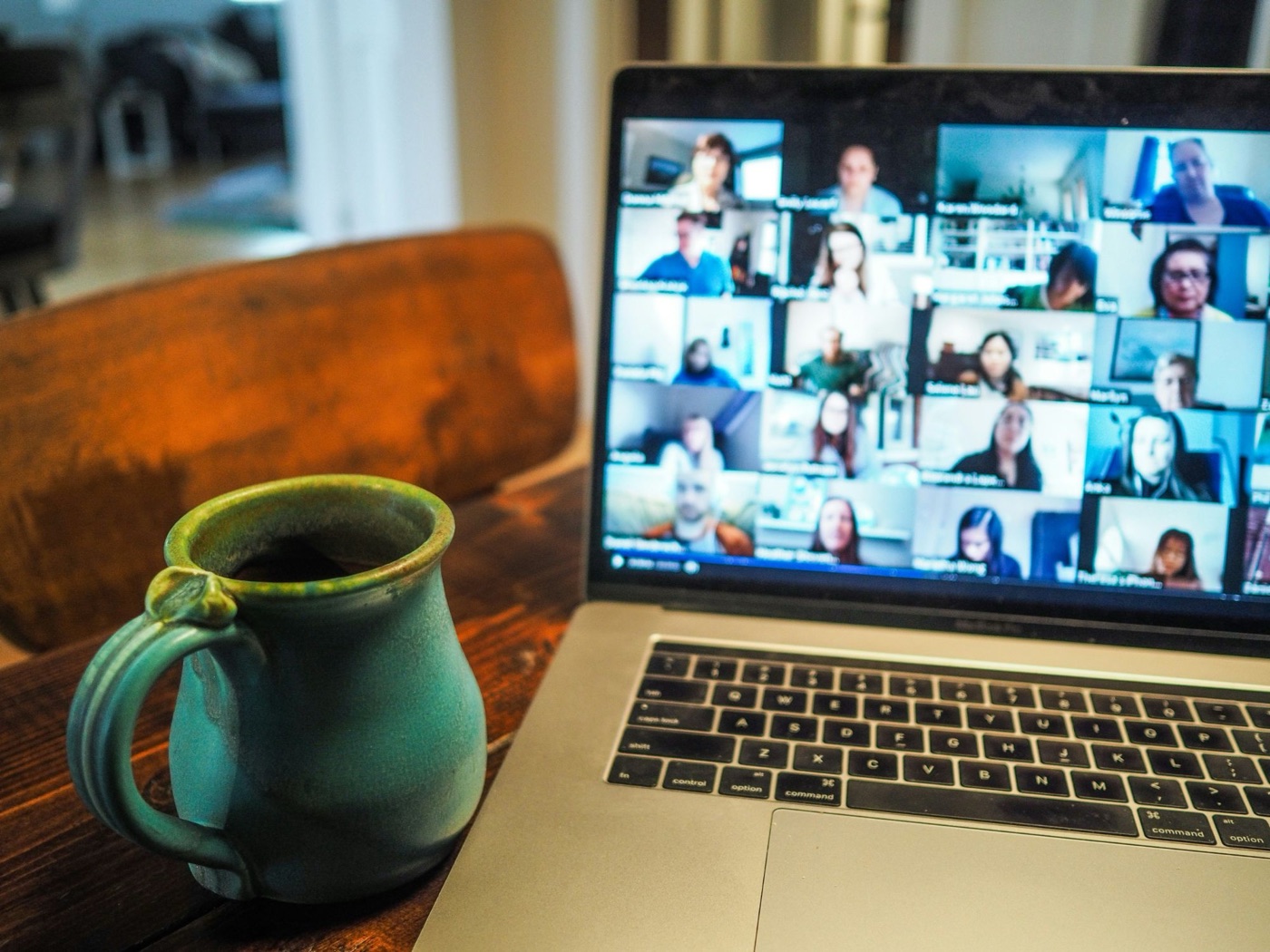 En bærbar computer med et videomøde og en kop kaffe ved siden af